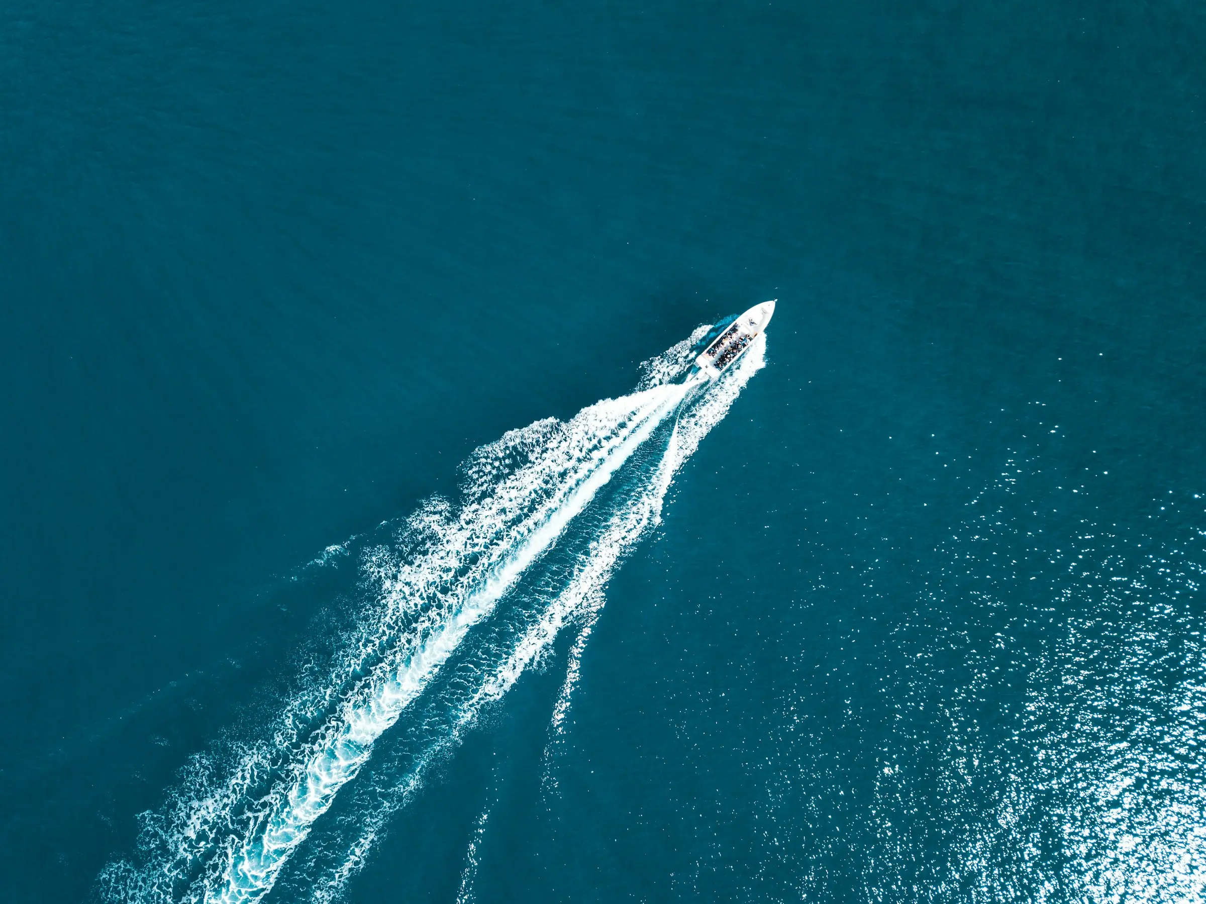 Vue aérienne d'un bateau à moteur traçant son sillage sur une mer Méditerranée bleu profond